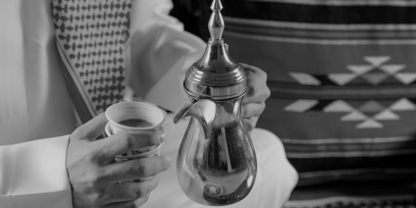 Arab Man serving traditional arabic coffee from a traditional pot.